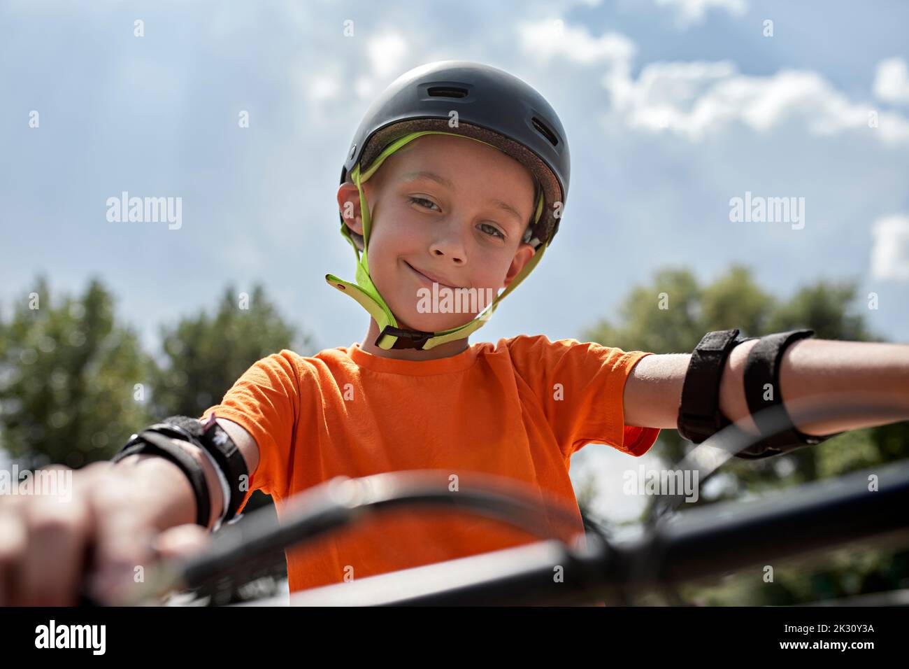 Lächelnder Junge mit Fahrradhelm und Schutzausrüstung Stockfoto