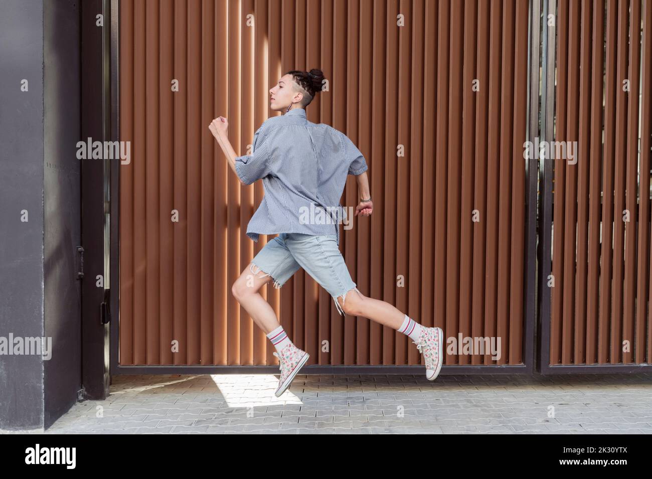 Nicht-binäre Person, die vor der Wand läuft Stockfoto
