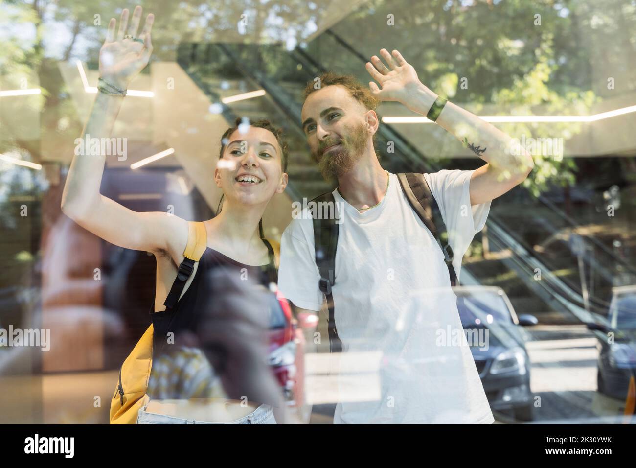 Ein Paar Hipster winkt durch das Glasfenster Stockfoto