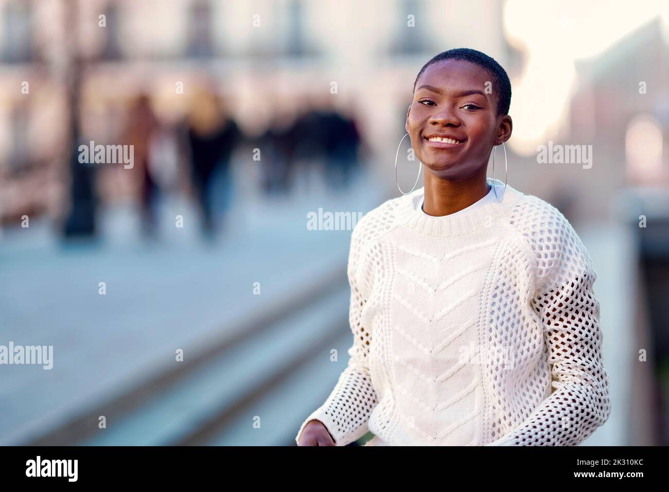 Lächelnde junge Frau mit Kreolen Stockfoto