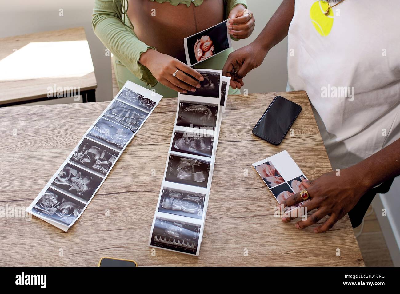 Schwanger Frau von Mann mit Ultraschall-Fotos von Baby auf dem Tisch Stockfoto