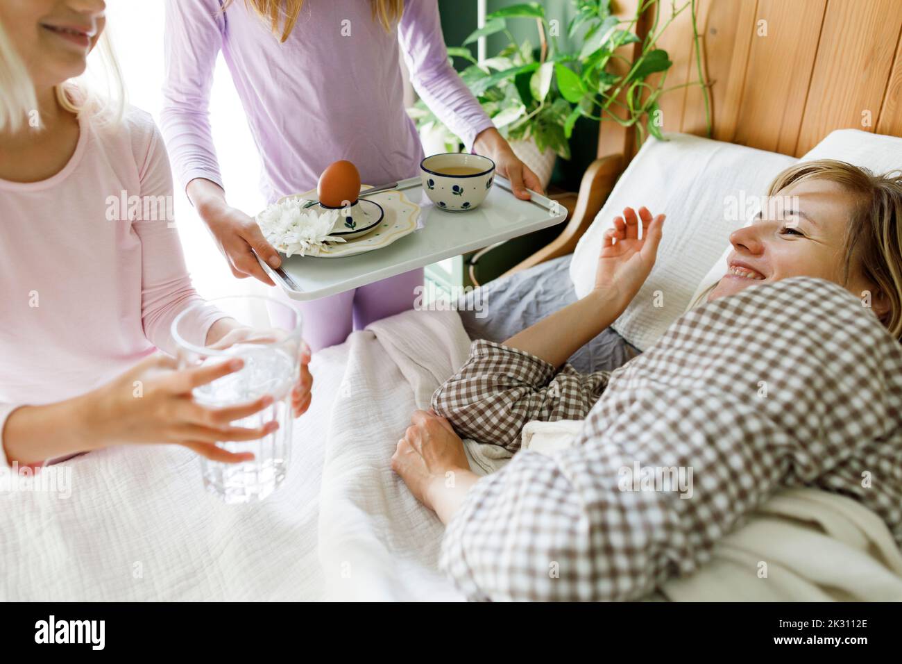 Töchter, die der Mutter im Schlafzimmer das Frühstück servieren Stockfoto