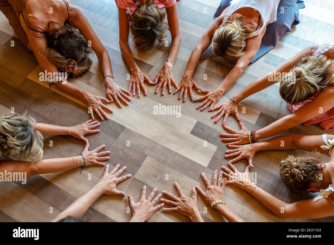 Gruppe von Freunden, die die Kinderpose üben, mit den Händen auf dem Boden Stockfoto