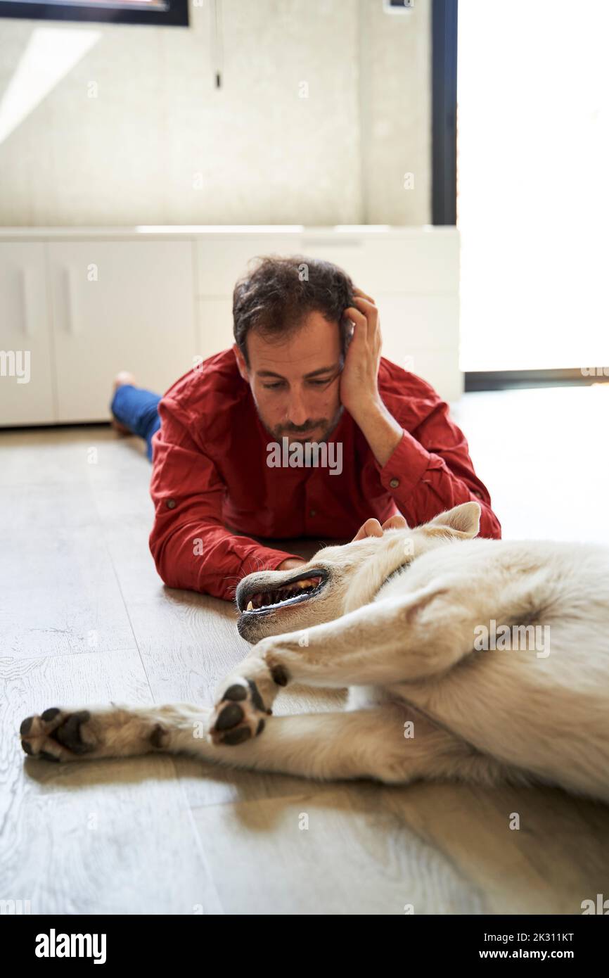 Mann, der sich hinlegt und seinen Hund ansieht Stockfoto