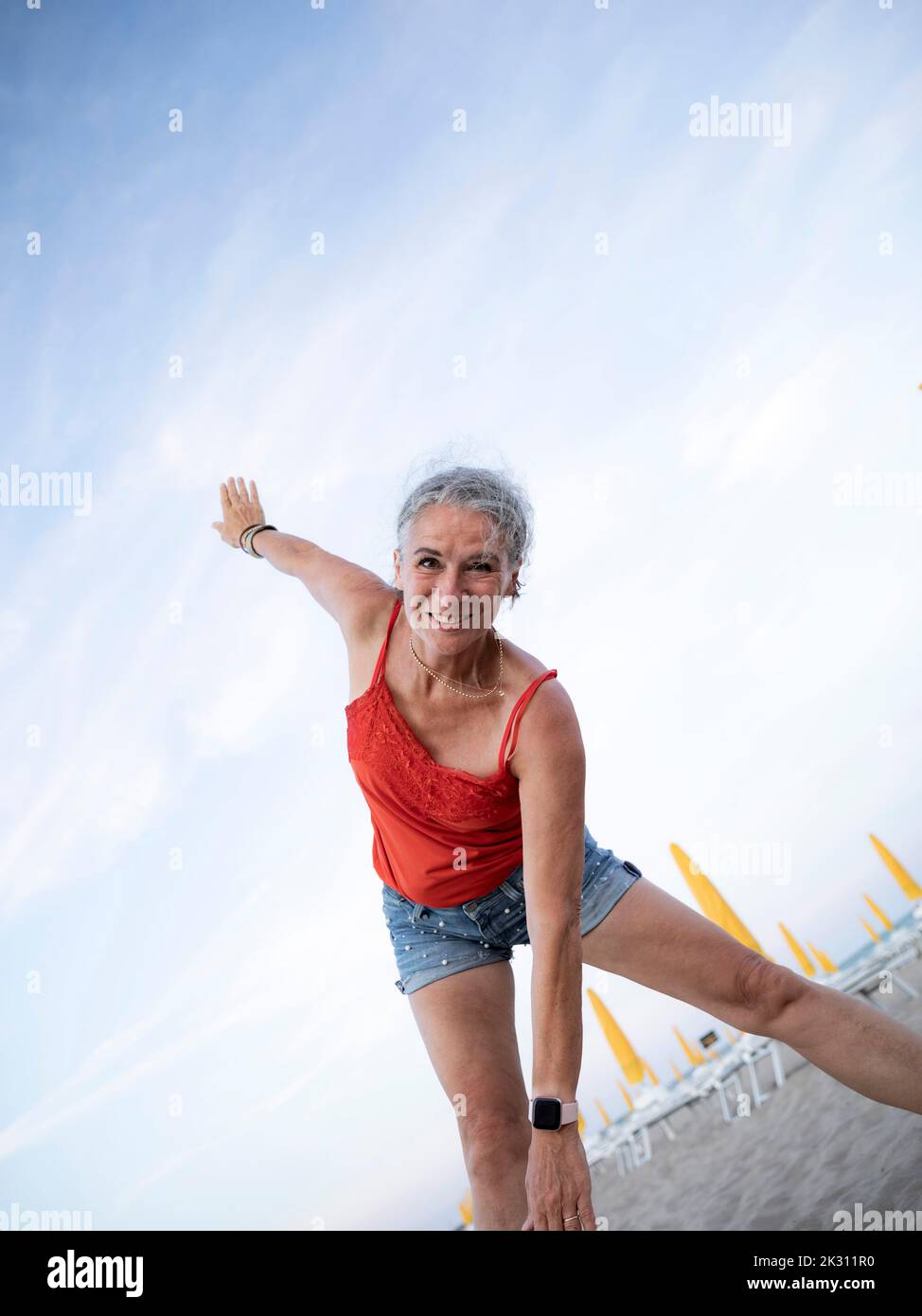 Glückliche ältere Frau, die am Strand Sport macht Stockfoto