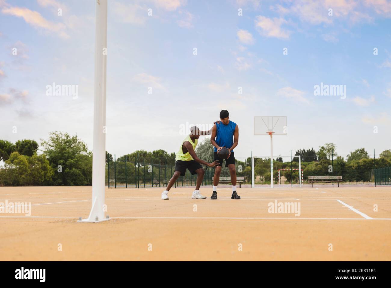 Vater lehrt Basketball-Fähigkeiten an Sohn auf dem Sportplatz Stockfoto