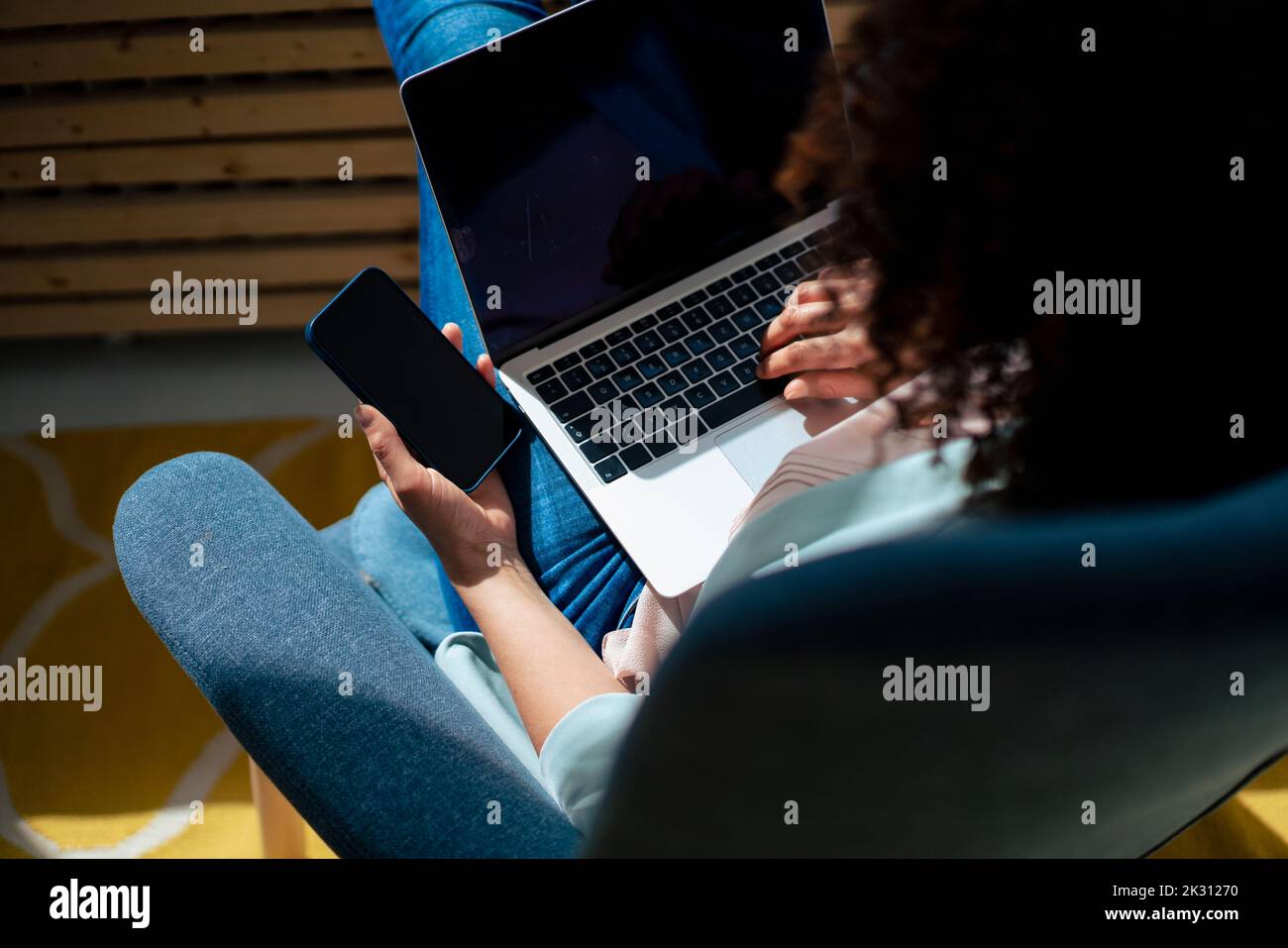 Geschäftsfrau mit Mobiltelefon und Laptop im Büro Stockfoto