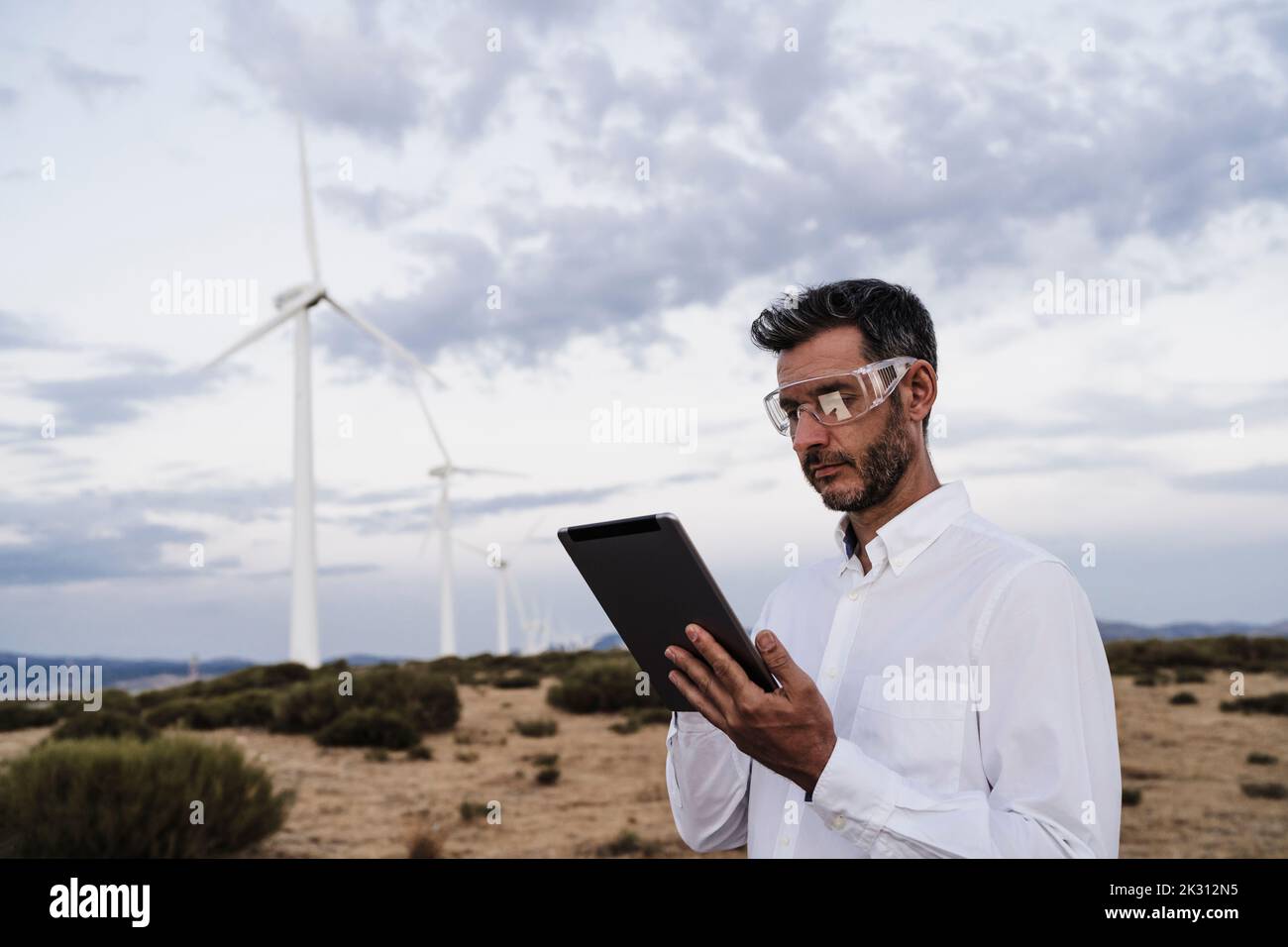 Techniker trägt Schutzbrille mit Tablet-PC im Windpark Stockfoto