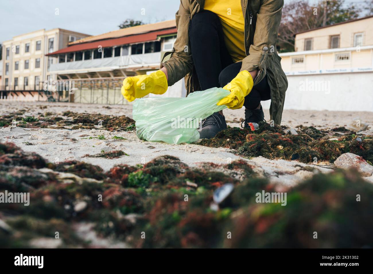 Frau sammelt Plastikmüll in Mülltüten am Strand Stockfoto