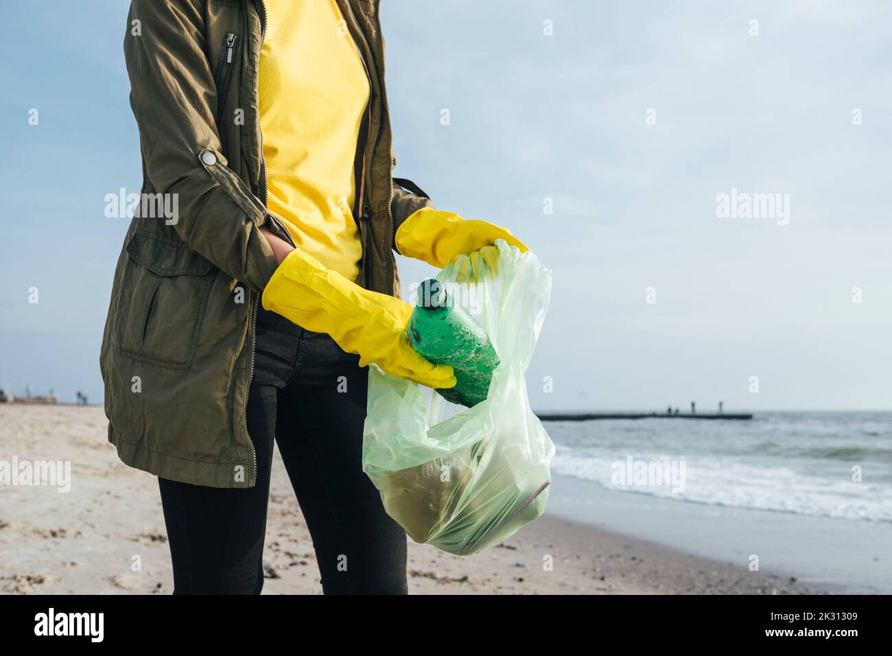Frau trägt Handschuhe und sammelt Plastikflaschen im Müllbeutel Stockfoto