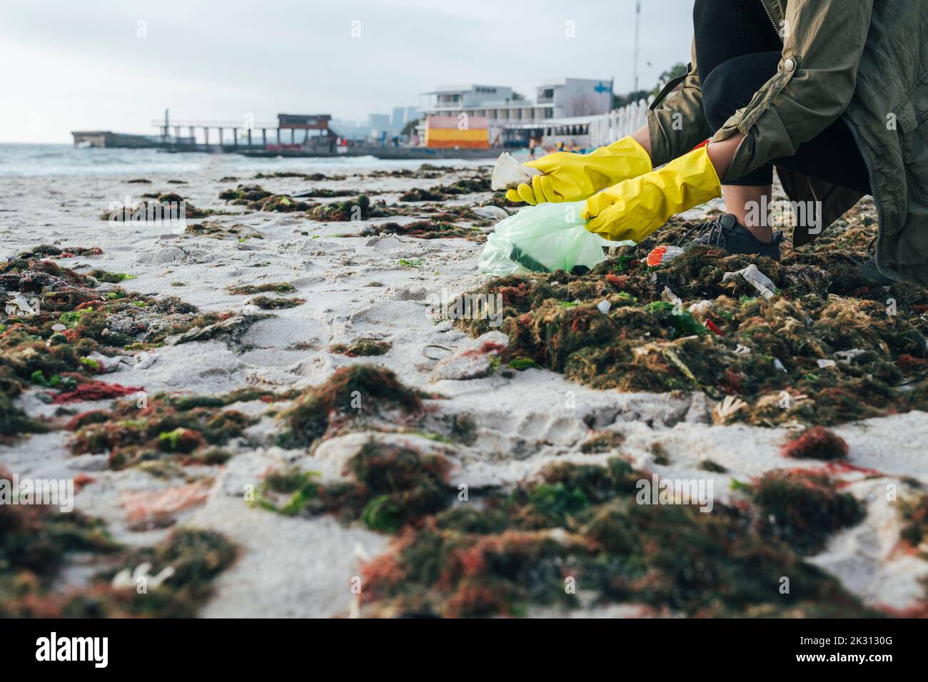 Umweltschützer trägt Handschuhe, die Plastikmüll am Strand sammeln Stockfoto