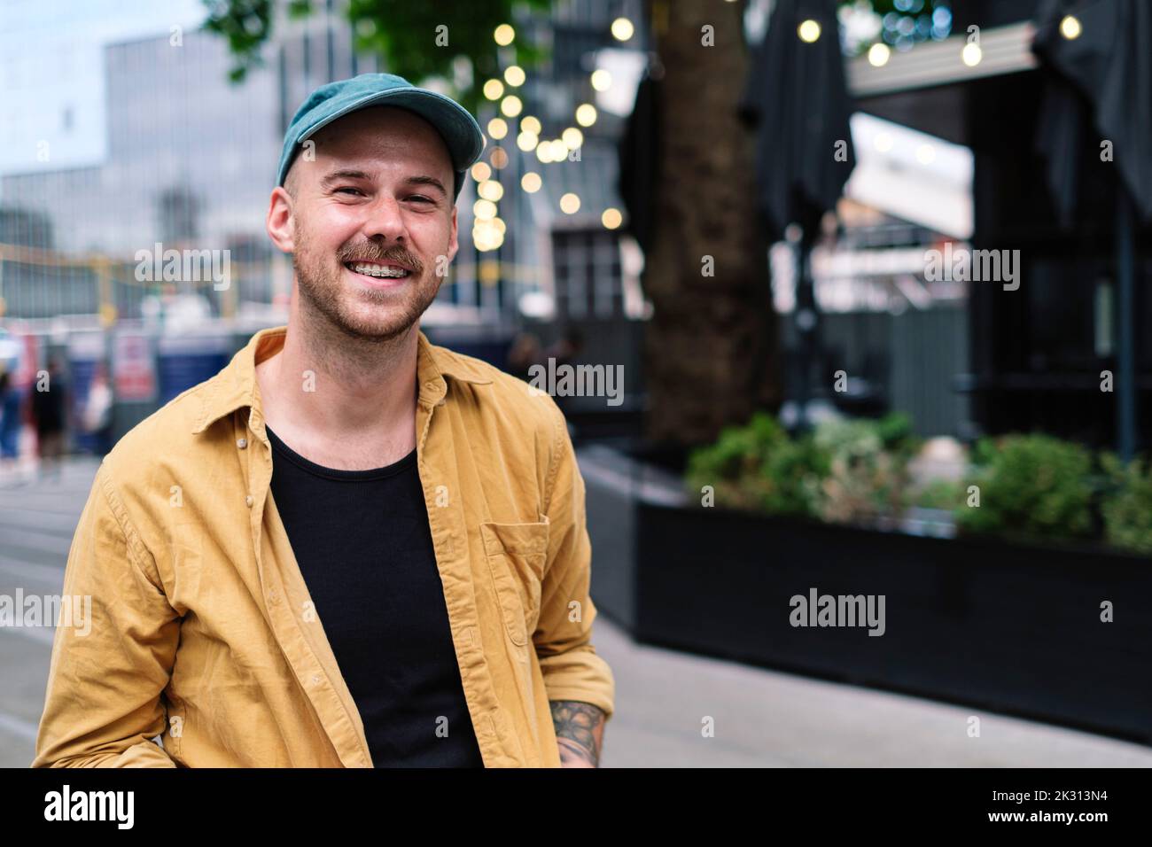 Lächelnder Mann mit Mütze und Hemd ohne Knopf Stockfoto