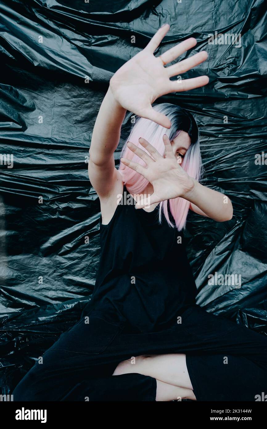 Frau zeigt Stoppgeste mit Händen vor schwarzem Plastikhintergrund Stockfoto