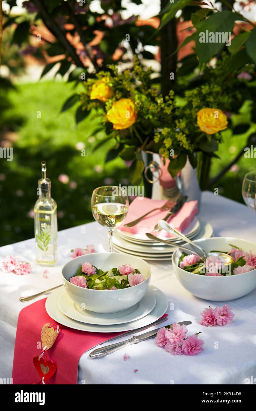 Eleganter, im Frühling dekorierter Tisch mit essbaren Blumen Stockfoto