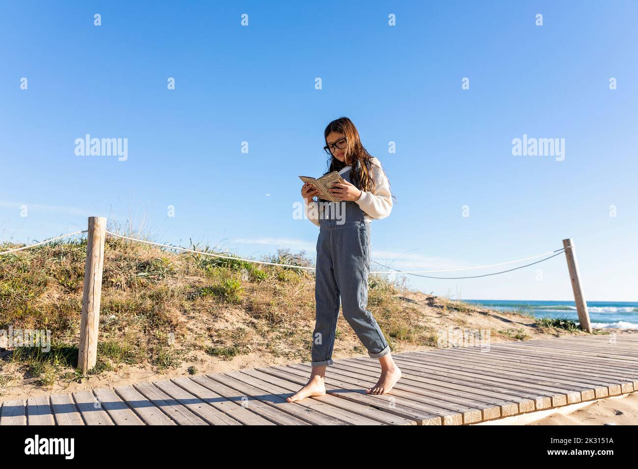 Mädchen liest Buch zu Fuß auf der Promenade Stockfoto