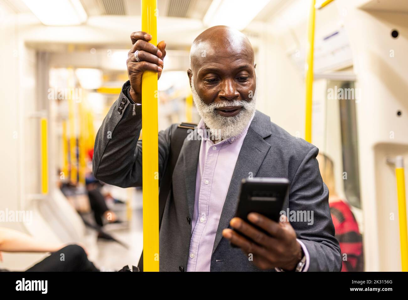Leitender Pendler mit Mobiltelefon und Haltebaum im Zug Stockfoto