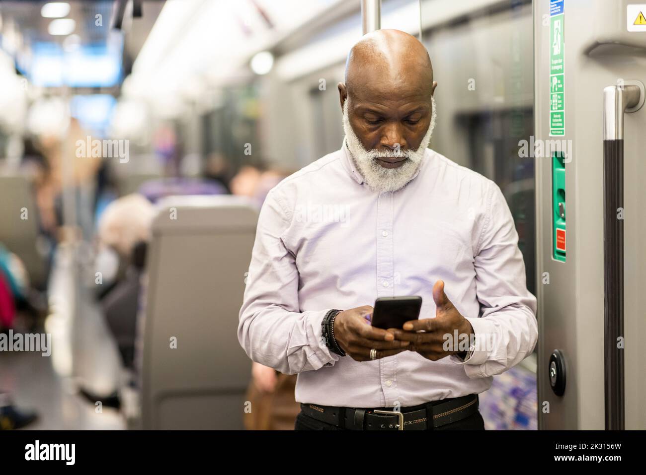 Glatze Senior Passenger mit Mobiltelefon im Zug Stockfoto