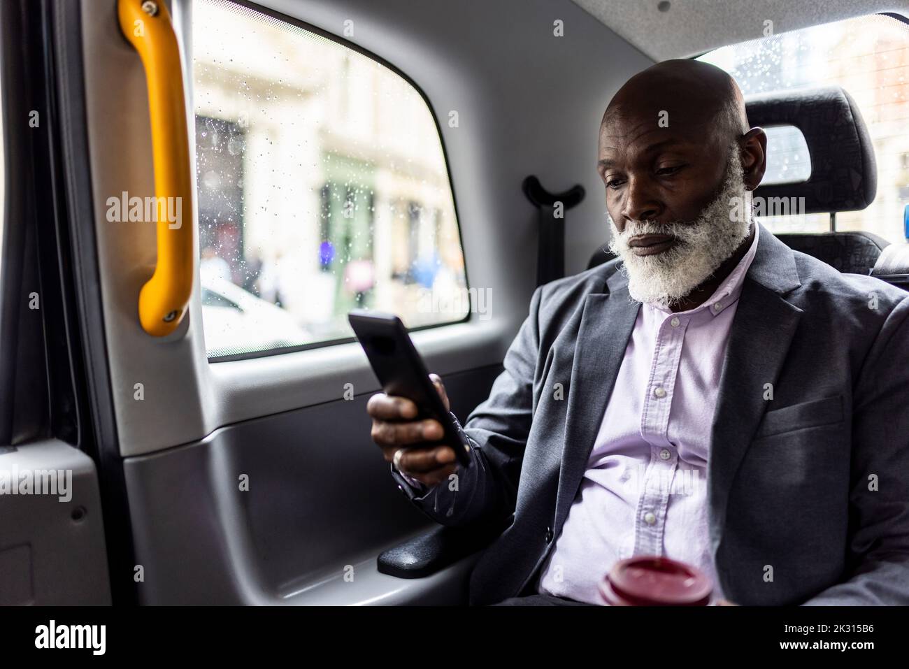 Älterer Passagier, der ein Mobiltelefon auf dem Rücksitz des Taxis verwendet Stockfoto