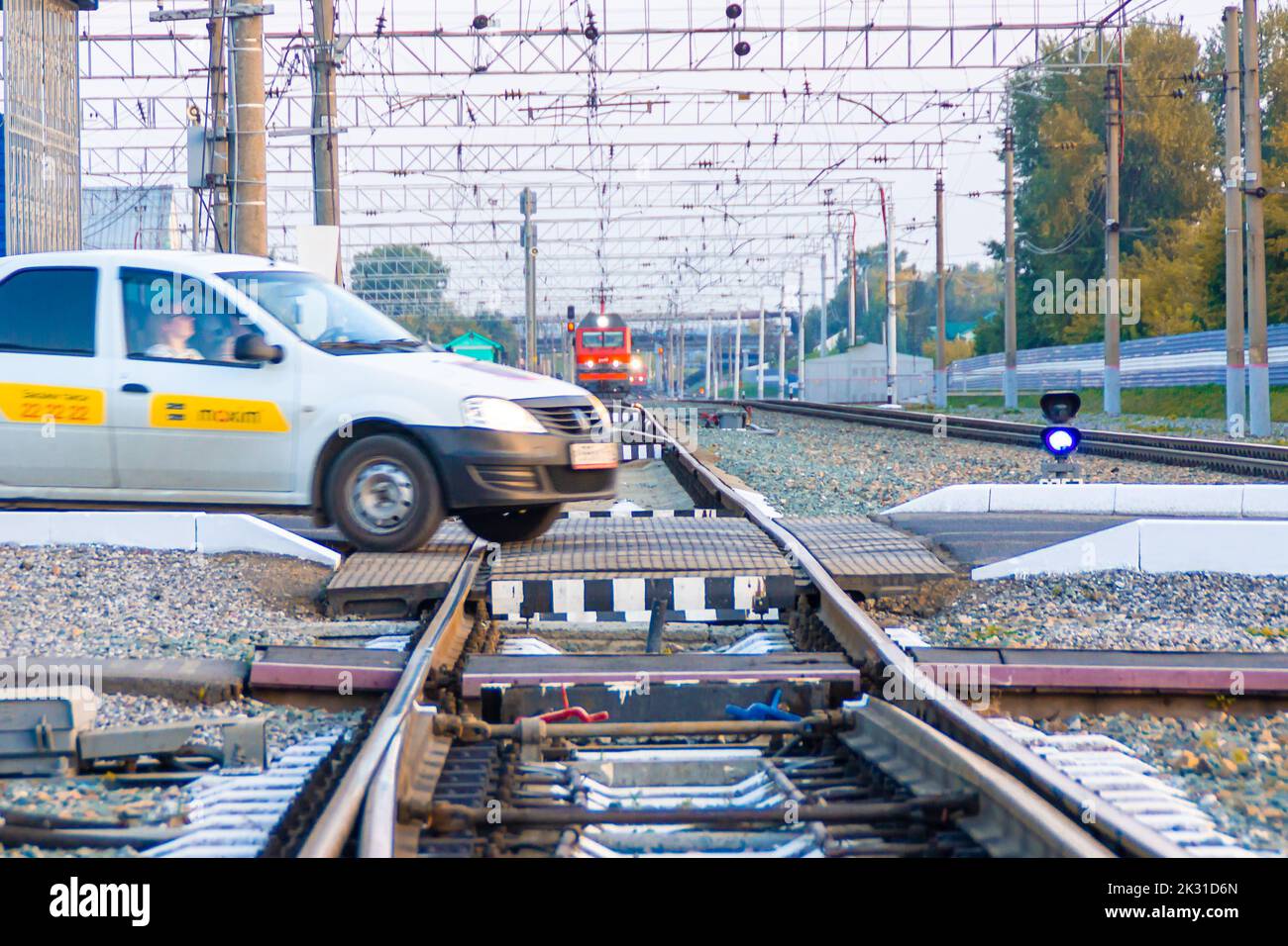 Kemerowo, Russland - 01. September 2022. Ein eilender Taxiwagen überquert gefährlich einen Bahnübergang vor einem herannahenden Zug, selektiver Fokus Stockfoto