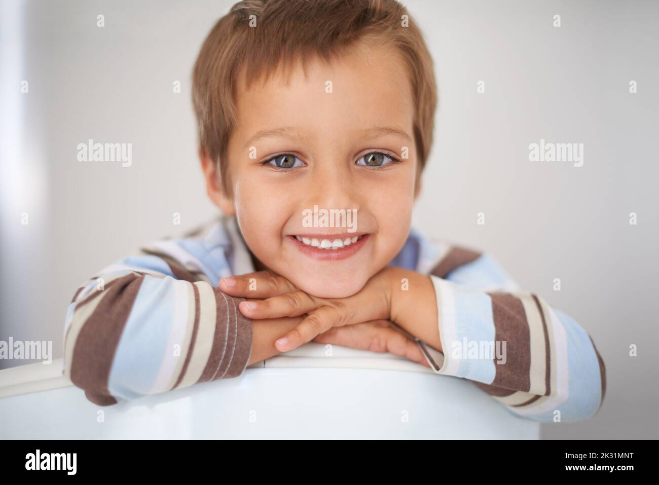 Ein Gesicht, zu dem man einfach nicht nein sagen kann. Ein Porträt eines glücklichen Jungen, der seinen Kopf auf seine Arme legte. Stockfoto