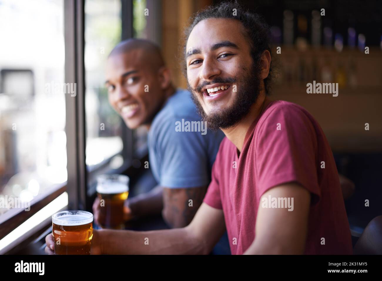 Ein gutes Lachen über ein gutes Bier. Ein kurzer Schuss von Freunden, die in einer Bar sitzen und Bier trinken. Stockfoto