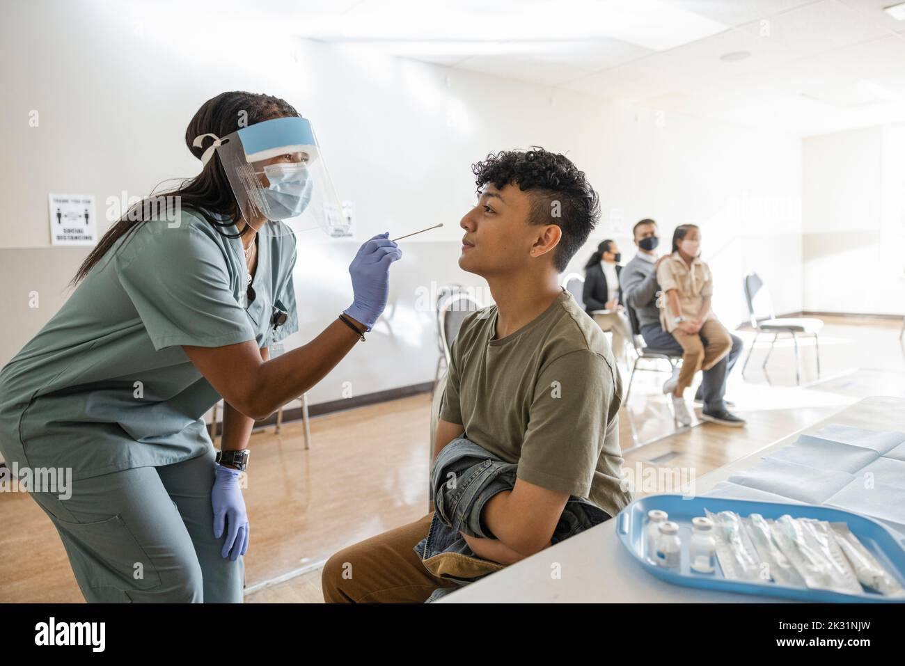 Krankenschwester in der PSA, die einen COVID-19-Nasenabstrichtest für Patienten in der Klinik durchzieht Stockfoto