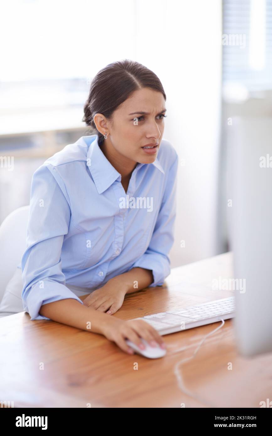 Verwirrt von der Arbeit, die zur Hand ist. Eine fokussierte junge Frau, die an ihrem Schreibtisch im Büro arbeitet. Stockfoto