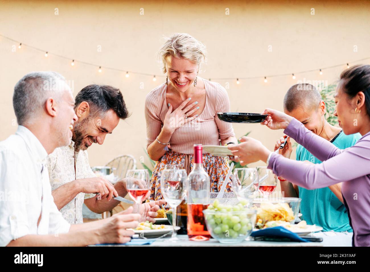 Eine Gruppe erwachsener Freunde, die sich bei einer Grillparty mit viel Essen und Getränken am Tisch treffen. Lifestyle-Konzept. Stockfoto