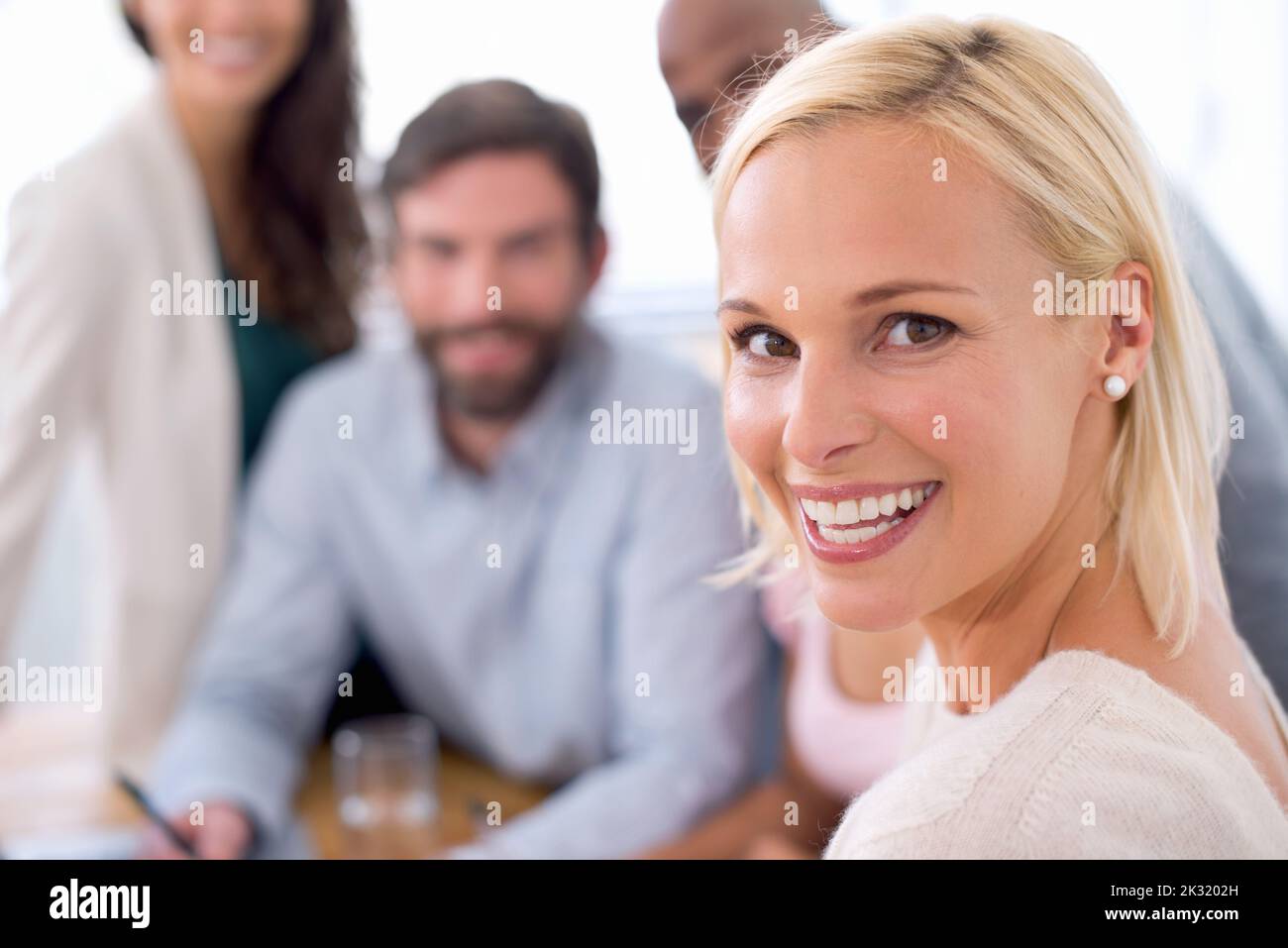 Die neueste Führungskraft des Unternehmens. Porträt einer lächelnden, schönen Geschäftsfrau bei einem Teamtreffen mit ihrem Team im Hintergrund. Stockfoto