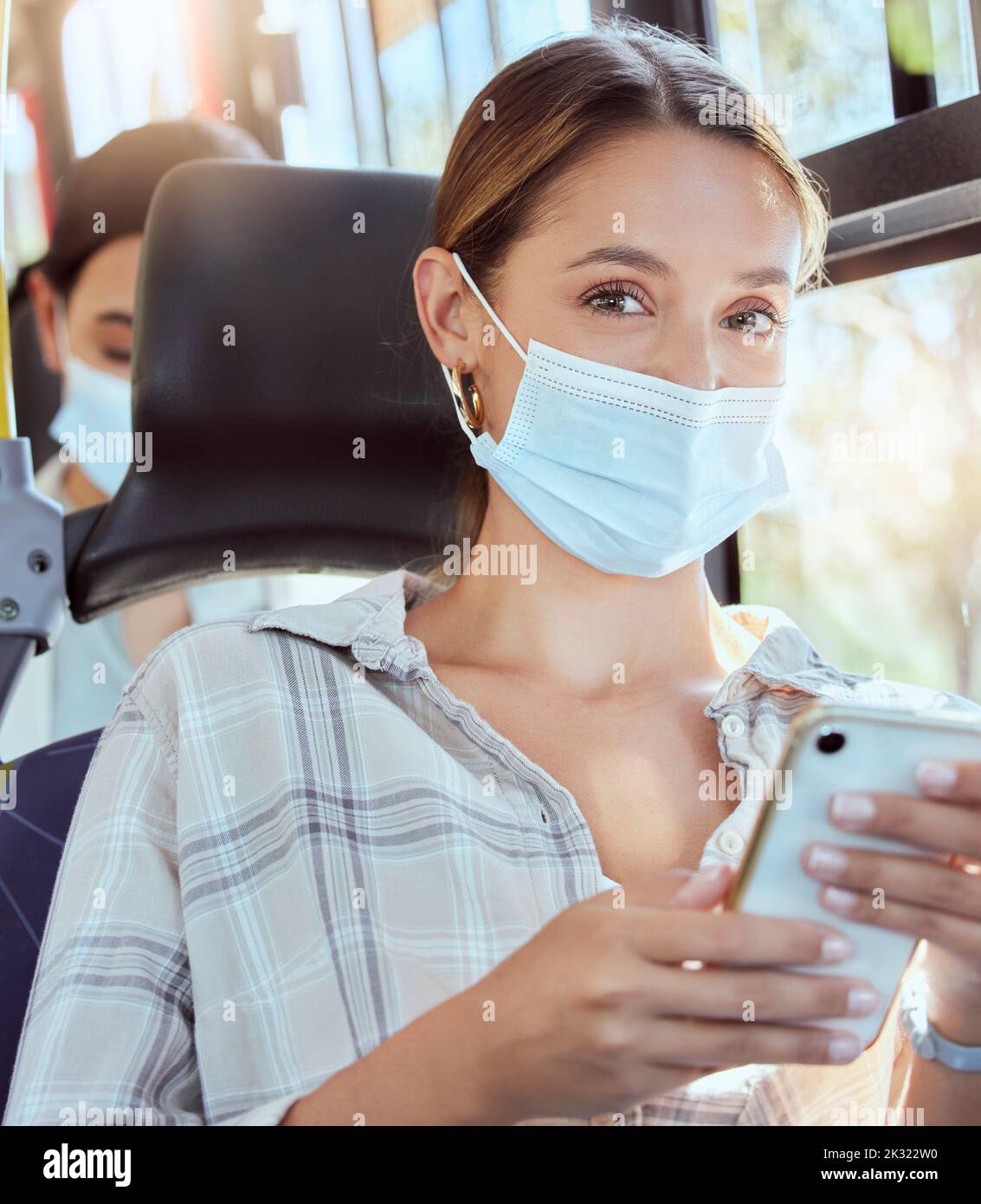 Covid, Bus und Maske Porträt mit Smartphone für öffentliche pendeln digitale Unterhaltung online. Mädchen, die mit Pandemieschutz für soziale reisen Stockfoto