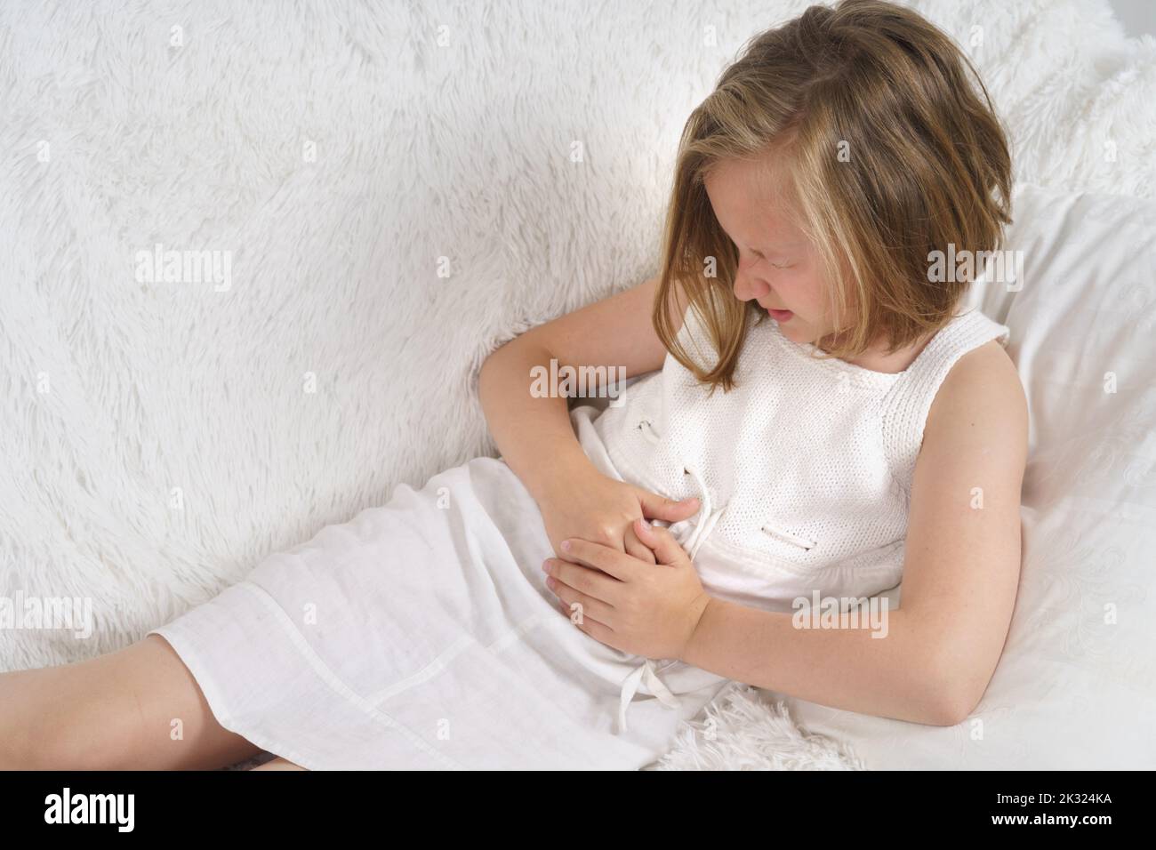Das Teenager-Mädchen quetscht sich vor Schmerzen die Hände auf den Bauch. Medizinisches Konzept. Stockfoto