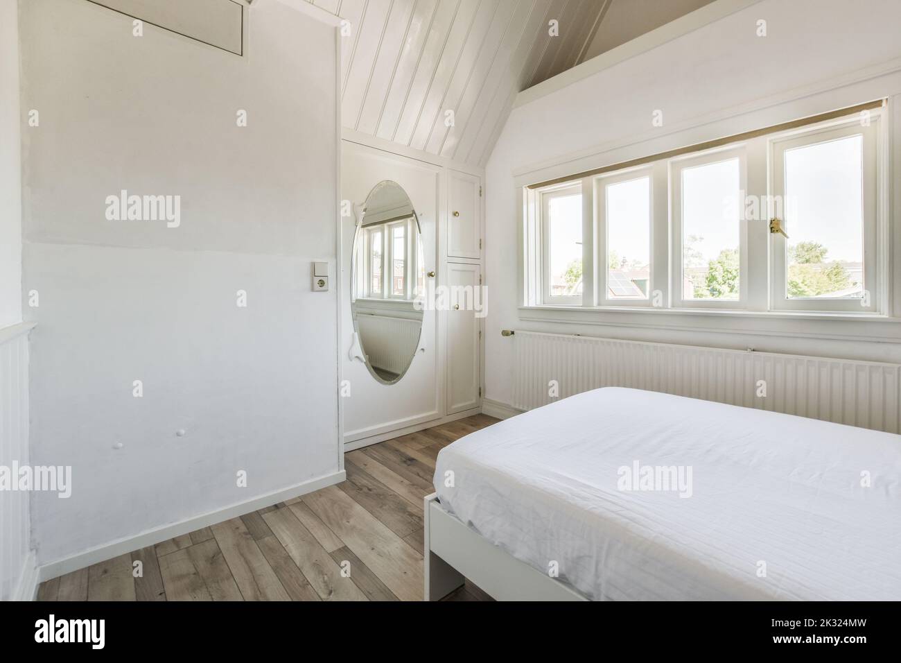 Modernes Wohndesign eines kleinen Herrenhauses mit weißen Wänden und einem weichen, gemütlichen Bett bei Tageslicht Stockfoto