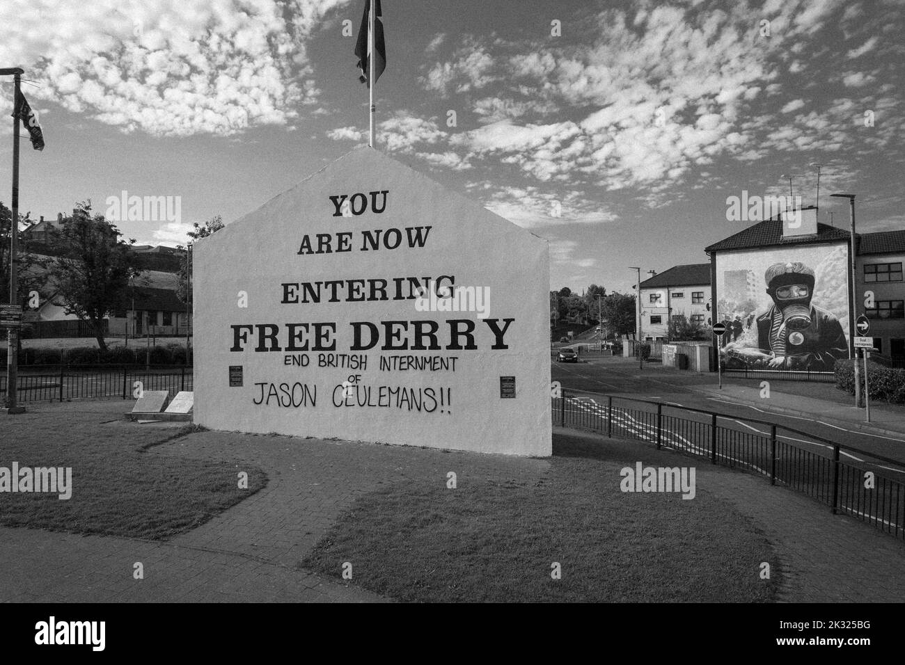 Schild in Free Derry mit Wandbild von Bogside Artists an der Seite des Hauses in Derry, Nordirland. Stockfoto