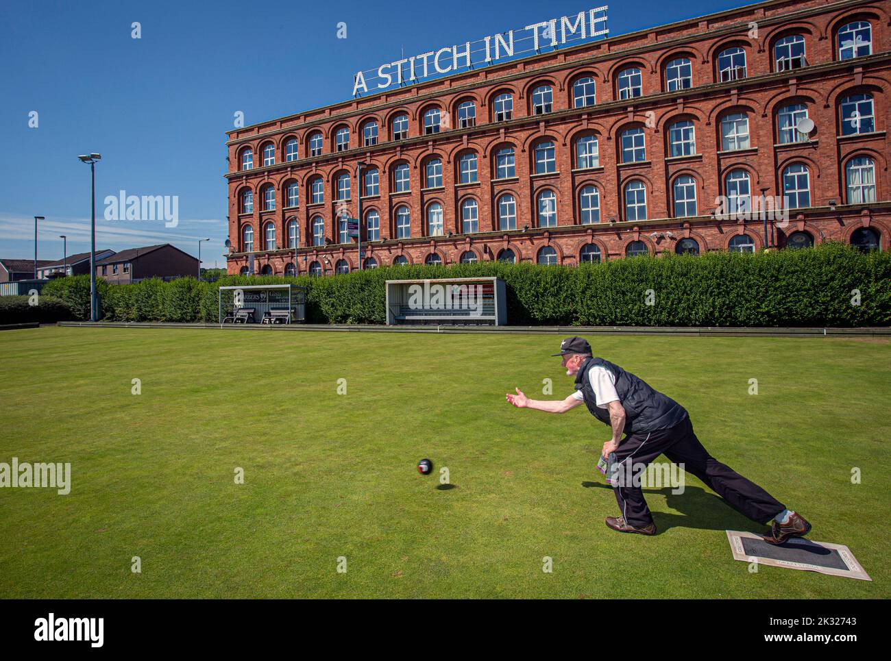 Mann spielt Bowls im Brooke Park Bowling Club vor der Old Rosemount Factory, Derry in Nordirland. Stockfoto