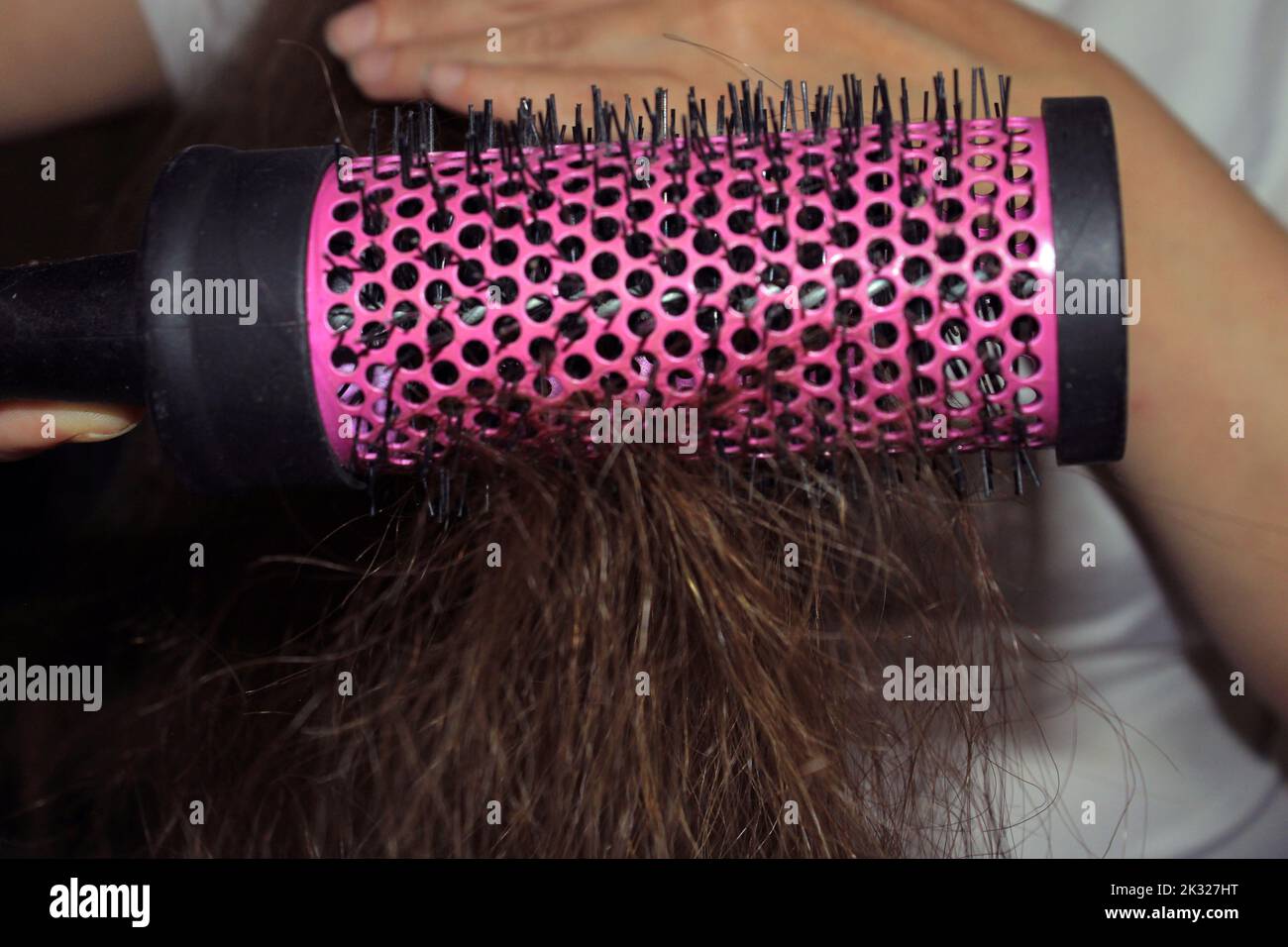 Ein Mädchen mit dunklen langen Haaren kämmt ihr Haar. Nahaufnahme der Haarbürste. Haarpflege. Haarausfall Problem. Stockfoto