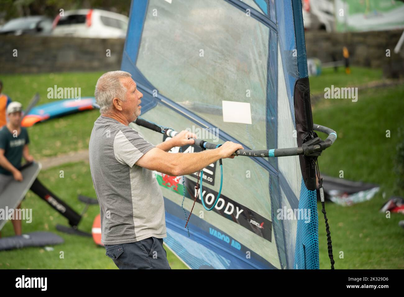 Ein pensionierter Mann stellt seine Ausrüstung auf, um beim Waterbourne Watersports Festival, Takapuna, an dem neuseeländischen nationalen Windsurf-Tragflächenboot-Rennen teilzunehmen. Stockfoto