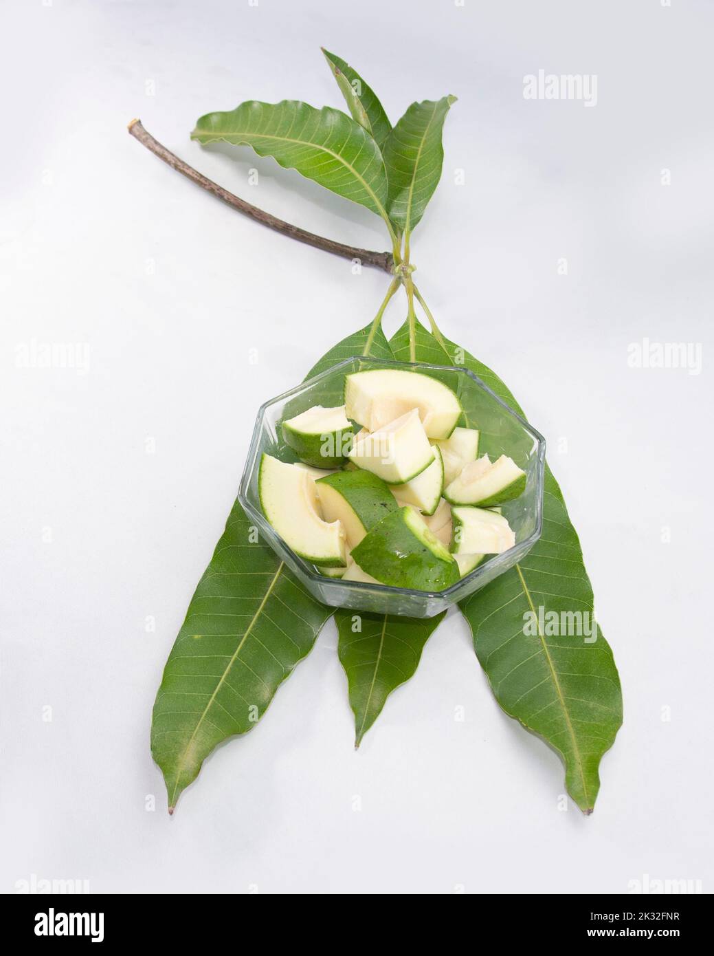 Scheiben roher grüner Mango auf Blättern. Stockfoto