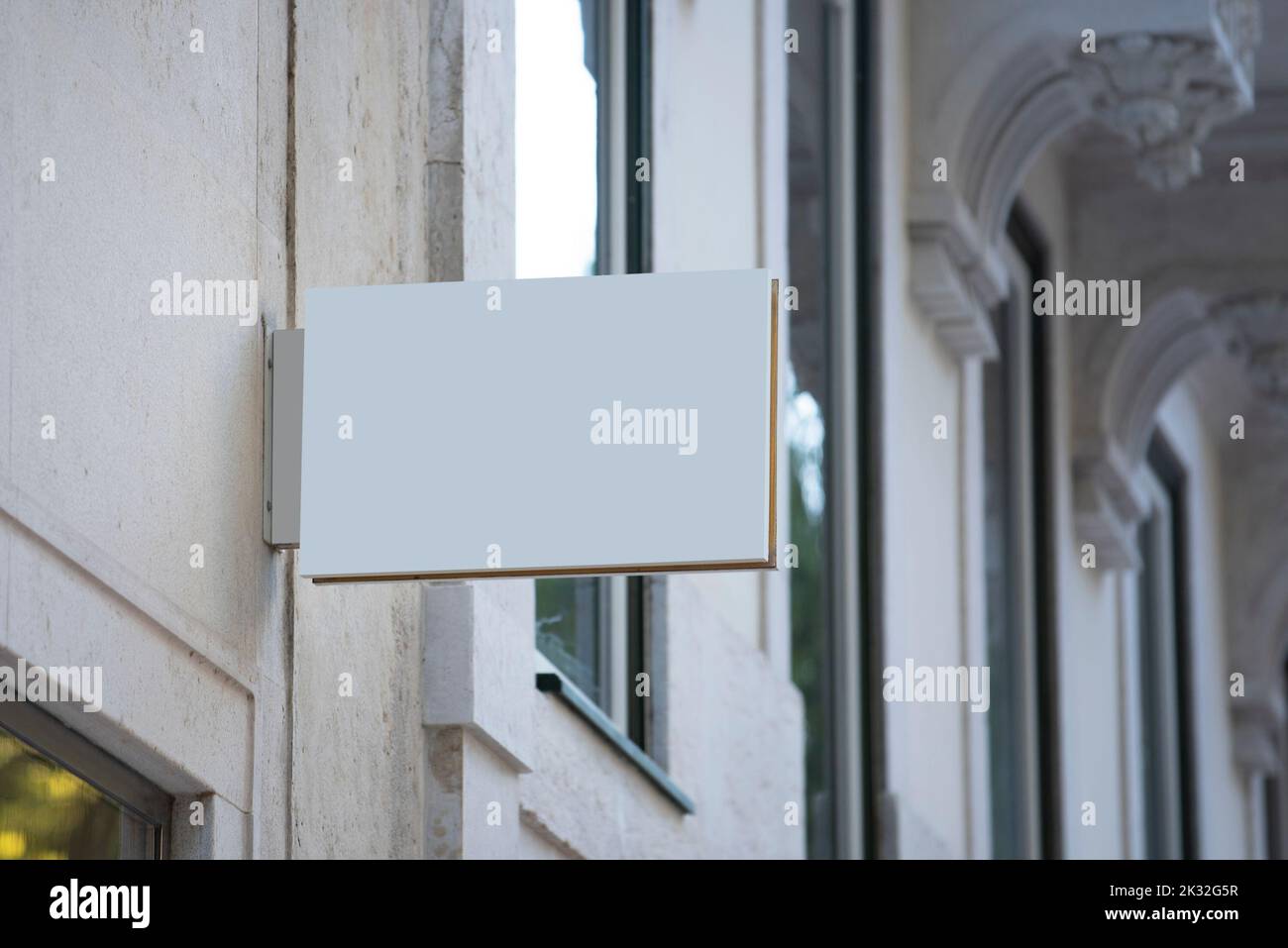 An der Wand eines alten klassischen Gebäudes hängt eine weiße horizontale Schildtafel mit weißen weißen Schildermockierungen Stockfoto