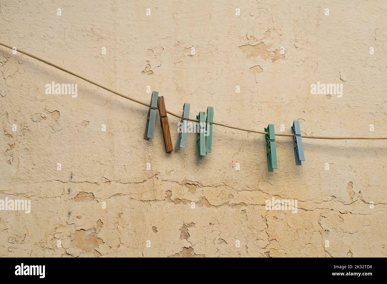 Alte Klamotten hängen an einer Wäscheleine, an einer alten, abblätternden Wand. Stockfoto