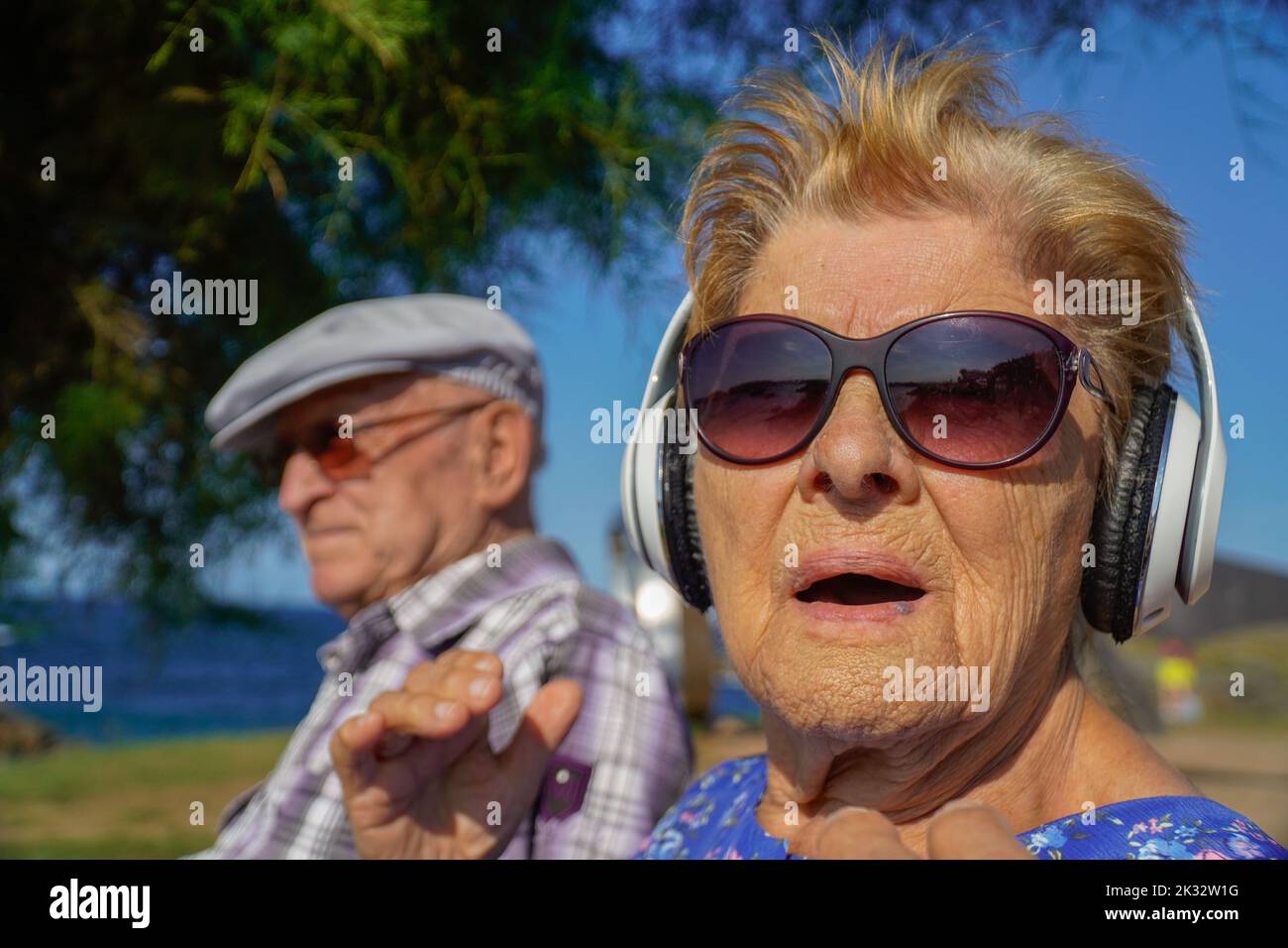 Alte Leute hören Musik in einem Park. Musiktherapie mit älteren Menschen. Aktives Alter Stockfoto