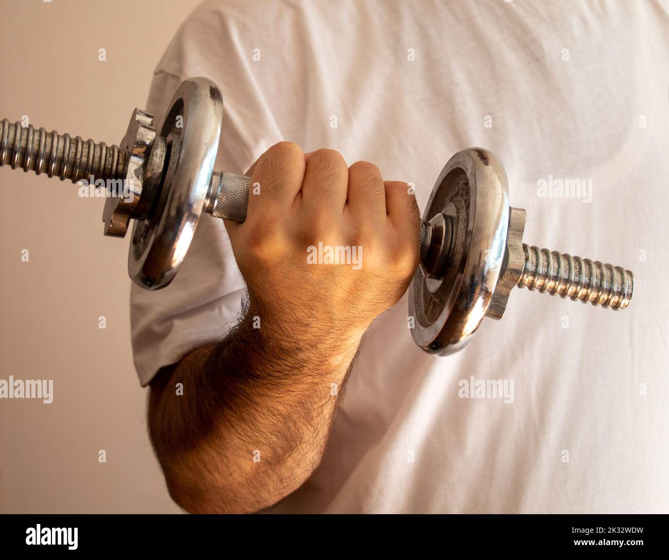 Eine Person Arm halten heben Hantel Motivation Anstrengung isoliert an der Wand, selektive Fokus Stockfoto