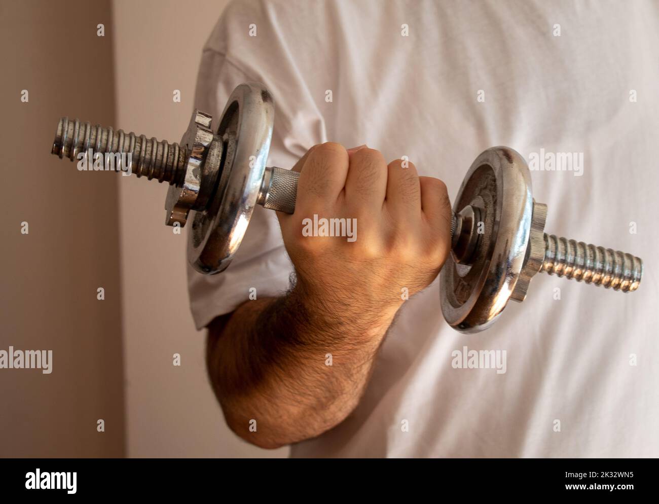 Eine Person Arm halten heben Hantel Motivation Anstrengung isoliert an der Wand, selektive Fokus Stockfoto