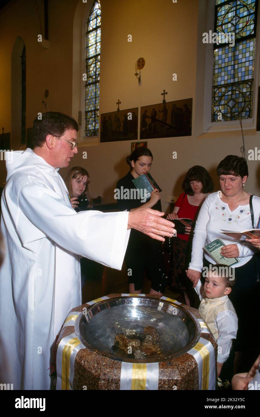 Eltern erneuern ihre Versprechen mit Priester und Paten in der St. Joseph's Catholic Church Roehampton London England Stockfoto