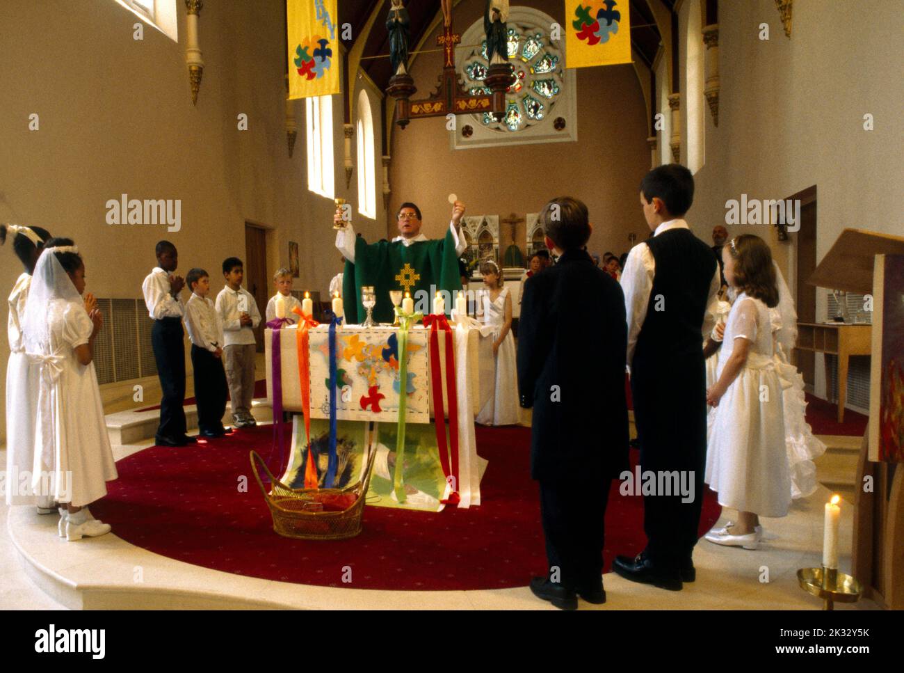 Priester am Altar, der die Eucharistie bei der Erstkommunion durchführt ...