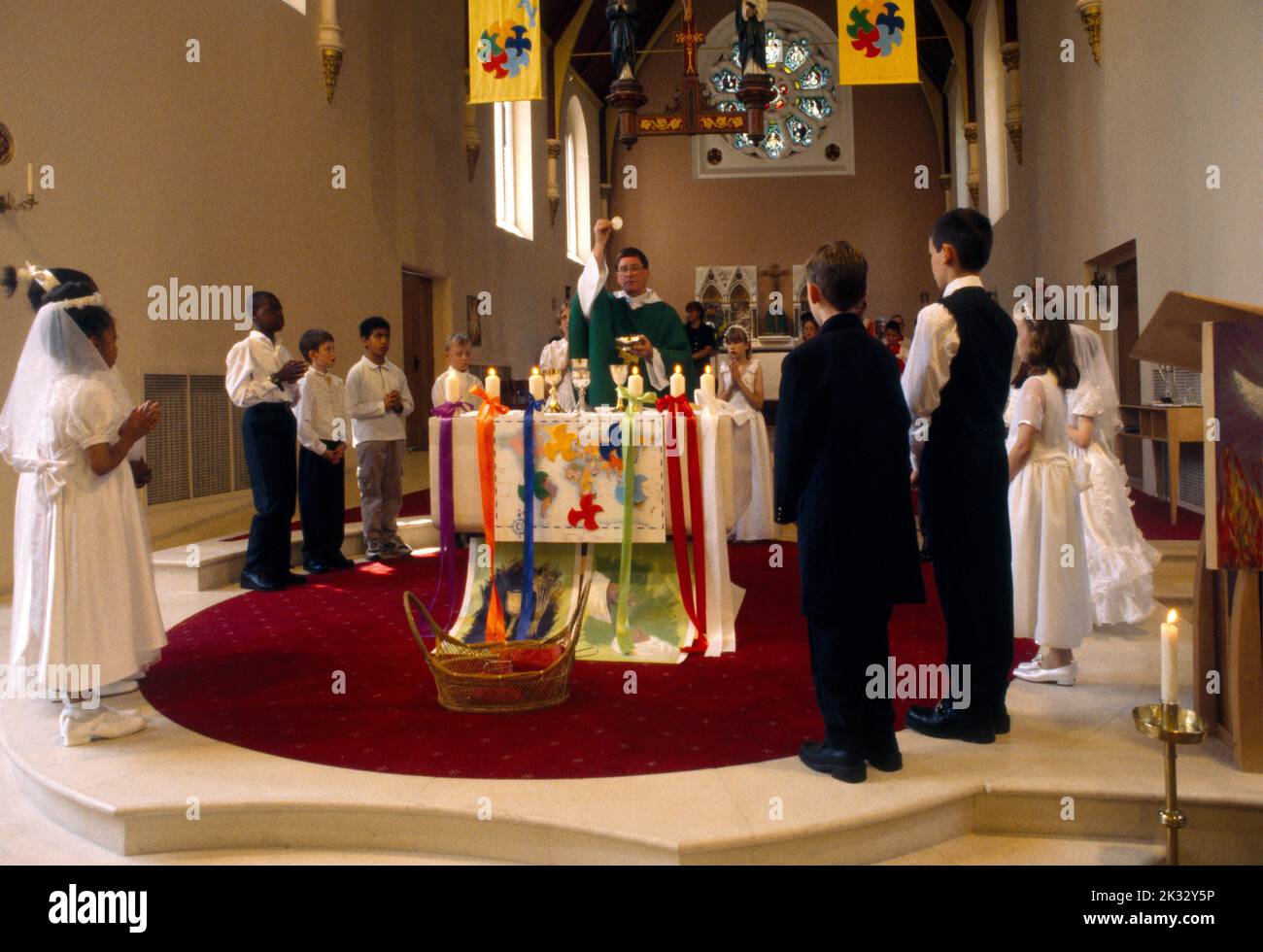 Priester am Altar, der die Eucharistie bei der Erstkommunion durchführt St. Joseph's Church Roehampton London England Stockfoto