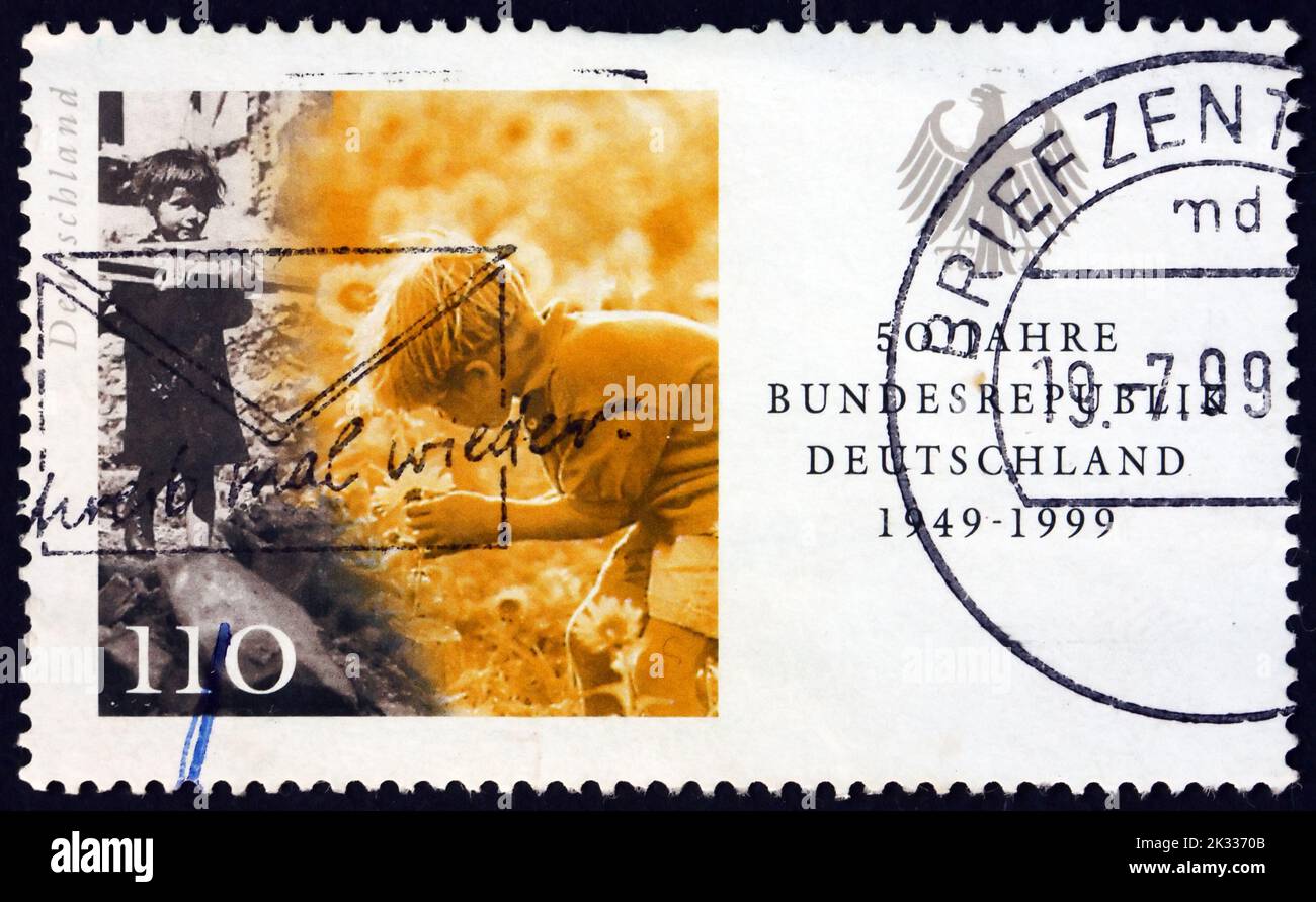 DEUTSCHLAND - UM 1999: Eine in Deutschland gedruckte Briefmarke zeigt das Holz tragende Kind und das Blumen pflücken, Szenen aus den Jahren 1949 und 1959, 50. Jahre Fe Stockfoto