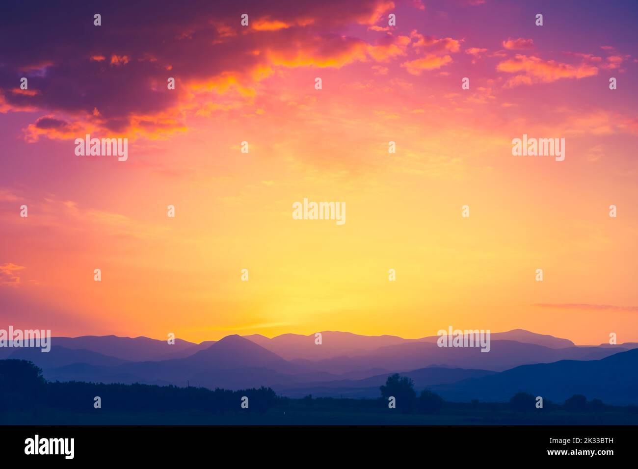 Schöne Bergkette mit Sonnenuntergangssonne in orangefarbenem Himmel mit bunten Wolken. Atemberaubende Naturkulisse. Natürliche Textur und Hintergrund Stockfoto