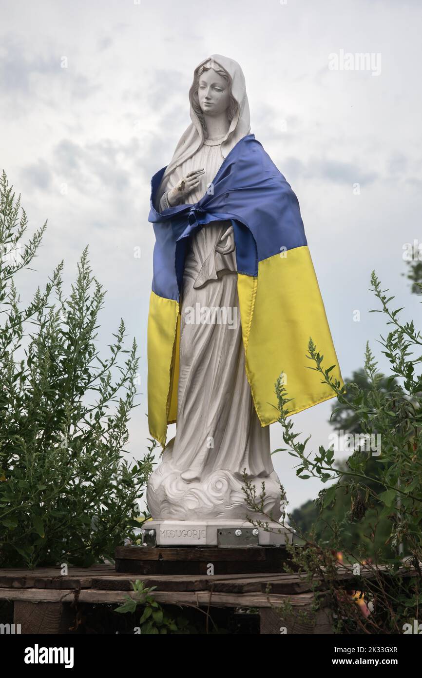 Die Statue der Mutter Maria an einem Kontrollpunkt ist in der Nähe von Pavlograd mit der ukrainischen Flagge umwickelt. Stockfoto