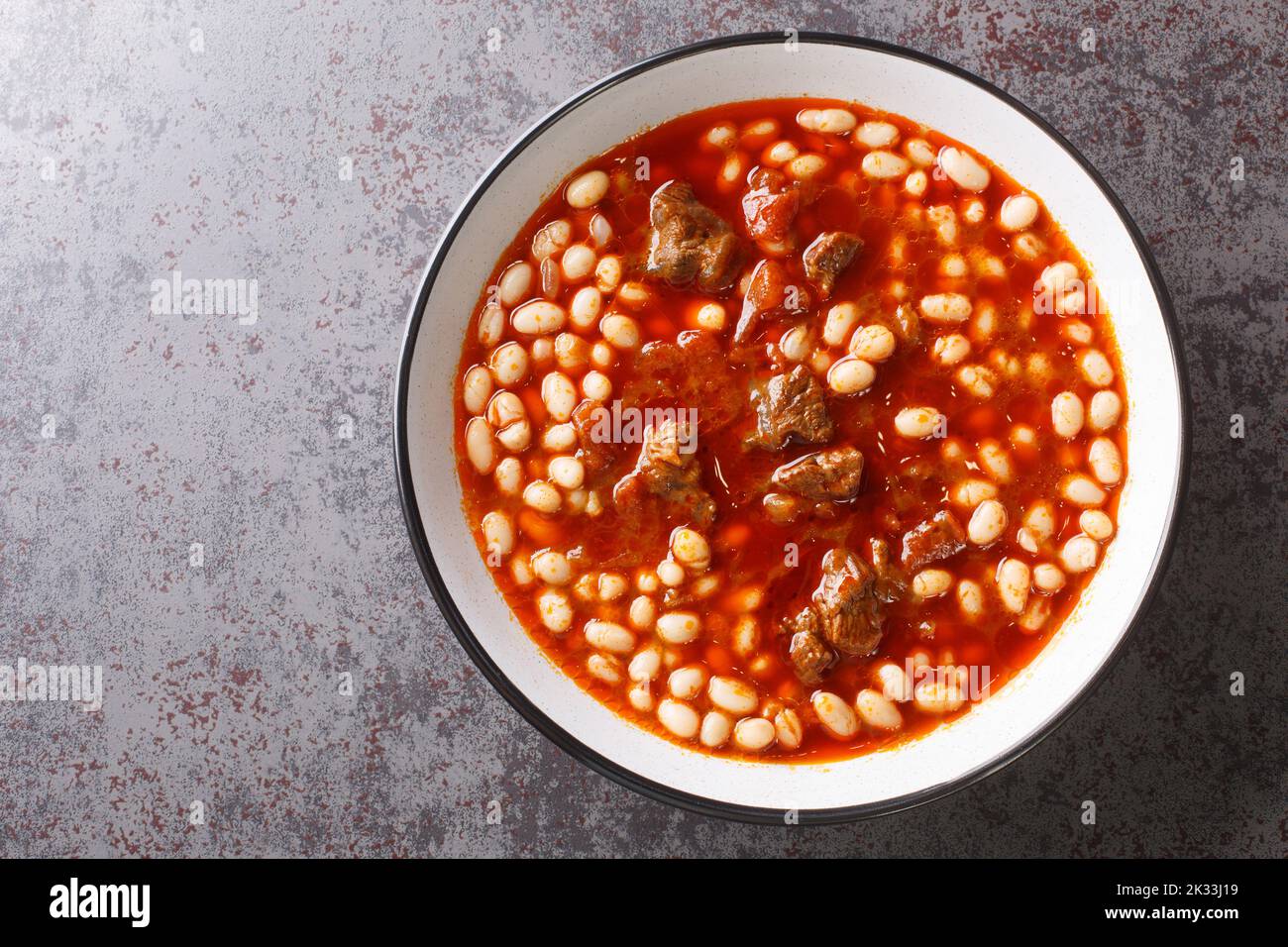 Würzige Kuru Fasulye aus Bohnen mit Lamm in Tomatensauce aus nächster Nähe in einer Schüssel auf dem Tisch einkochen. Horizontale Draufsicht von oben Stockfoto