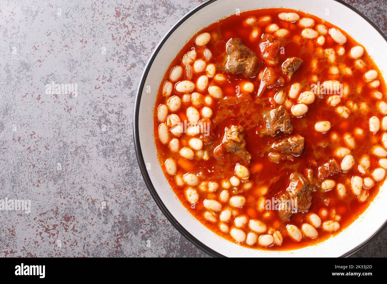 Scharfe türkische Küche Kuru Fasulye aus Bohnen mit Lamm in Tomatensauce in einer Schüssel auf dem Tisch. Horizontale Ansicht von oben Stockfoto